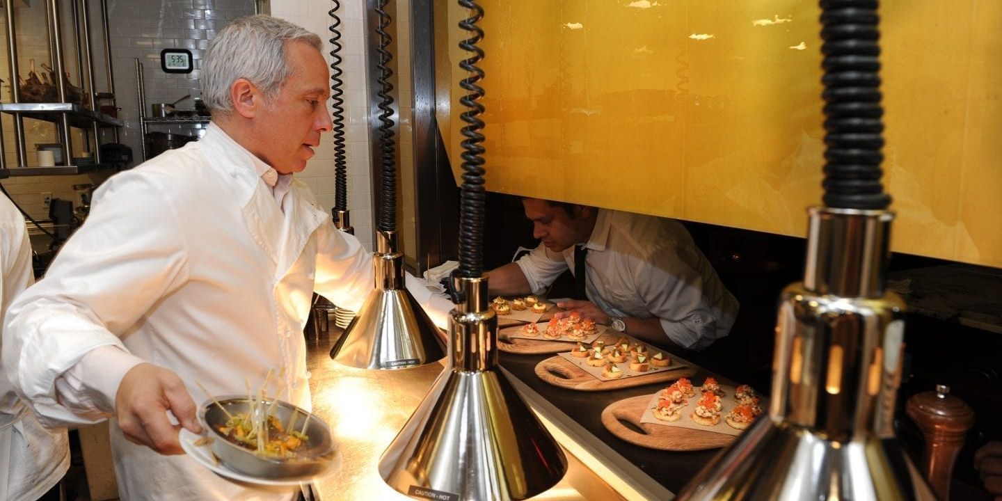 Chief Geoffrey Zakarian passing food to a server