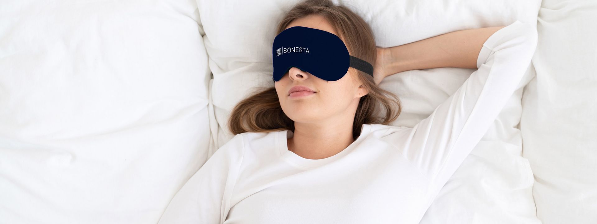 Woman sleeping on bed with Sonesta sleeping mask